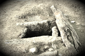 A Bronze Age stone burial chamber on Dartmoor, photographed in tones of sepia. The cap-stone is displaced from its proper position.